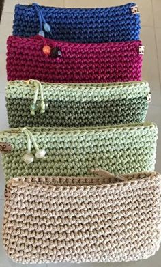 four crocheted purses are lined up on the floor in different colors and sizes