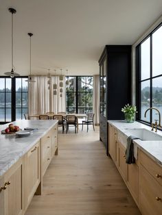 a large kitchen with wooden cabinets and marble counter tops next to a dining room table