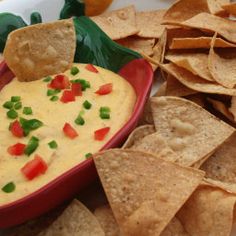 a red bowl filled with dip surrounded by tortilla chips