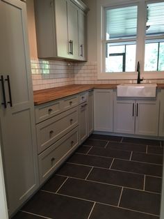 a kitchen with white cabinets and black tile flooring