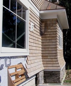 a wooden bench sitting in front of a house next to a window on the side of a building