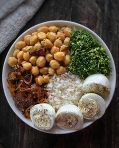 a white plate topped with eggs, rice and other foods on top of a wooden table