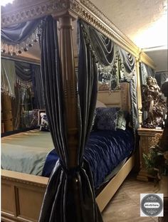 a canopy bed with blue sheets and drapes on the sides, in a bedroom