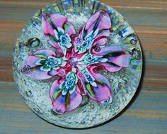 a glass plate with pink flowers on it sitting on a table next to a wooden surface