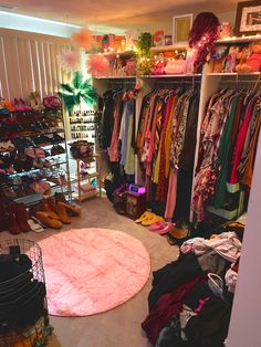 a closet filled with lots of clothes and other items on shelves next to a pink rug