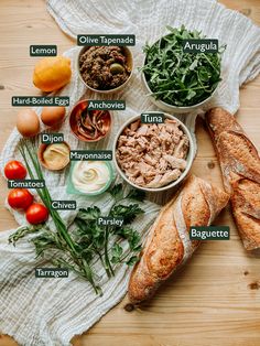 an assortment of food on a table including bread, tomatoes, meats and other items