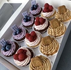 a box filled with cupcakes covered in frosting and fruit