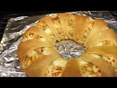 a bundt cake sitting on top of aluminum foil covered in cheese and toppings