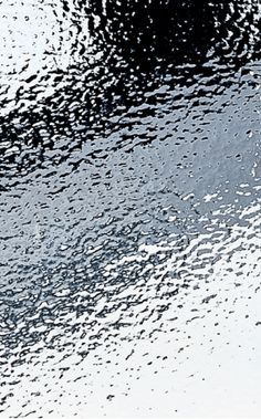 the reflection of an umbrella in water on a rainy day with rain drops falling off it