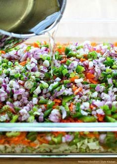 someone is pouring dressing into a casserole dish with chopped vegetables and carrots