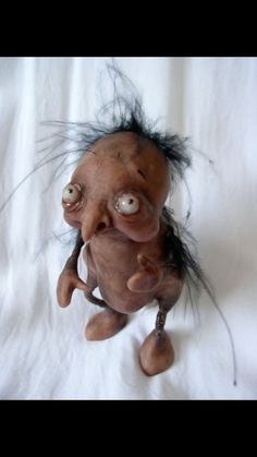 an old trolly doll with hair on it's head and eyes, sitting on a white sheet