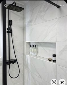 the shower head is mounted on the wall next to the shelves in the shower stall