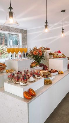 a buffet with oranges, wine glasses and other food on the counter in front of it