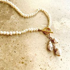 For those who prefer smaller pearls this beach inspired boho style fashion piece features dainty Grade A freshwater pearls finished with a 24k gold plated toggle clasp and trio of tiny seashell charms.  This necklace has been hand knotted for the best quality finish and comes in a classic 17" length. Perfect for Summer it's a timeless design that works for every occasion. Wear alone or layer with your other pieces to create a more casual bohemian style. Also makes a gorgeous gift ❤️ Presented in Luxury White Shell Necklace With Pearl Charm, Dainty Pearl Charm Necklace For The Beach, Adjustable Pearl Charm Necklace For Beach, Gold Pearl Necklace With Pearl Charm For Beach, Elegant Beach Charm Necklaces With Pearl, Elegant Pearl Charm Necklaces For Beach, Adjustable Pearl Drop Necklace For Beach, Casual Bohemian Style, Spiral Shell