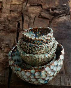 three bowls stacked on top of each other in front of a piece of driftwood