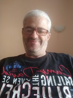 a man with white hair and glasses smiles for the camera while wearing a t - shirt that says camp david