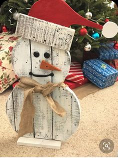 a snowman made out of wooden planks sitting in front of a christmas tree