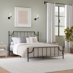 a bedroom with green walls and white carpeted flooring has a black iron bed frame