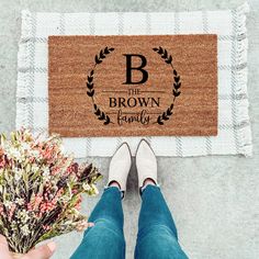 a person holding flowers in front of a door mat that says the brown family