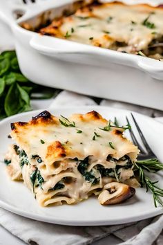 a white plate topped with lasagna covered in cheese and herbs next to a casserole dish