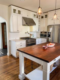 a large kitchen with white cabinets and wooden counter tops, an island in the middle