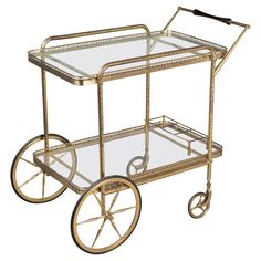 an antique brass serving cart with glass top