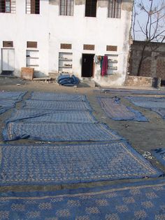 several blue rugs are laid out in front of a building