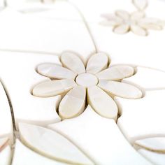 a close up view of a flower design on a tile floor with white and beige colors