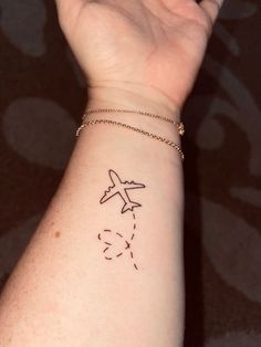 a person's arm with a small tattoo on the wrist and an airplane drawn on it