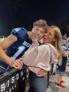 a man and woman standing next to each other at a football game