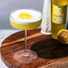 a yellow drink in a coupe glass on a wooden tray