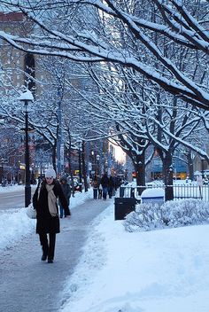 a woman walking down a snow covered sidewalk