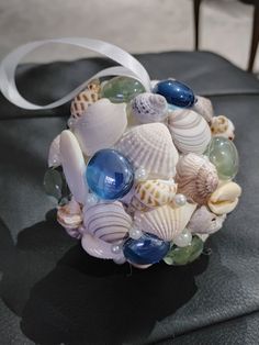 a bouquet made out of seashells and pearls on a black leather chair with a white ribbon