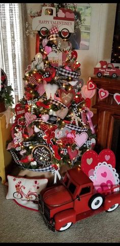 a christmas tree decorated with red, black and white hearts is next to a firetruck