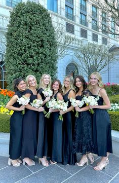 a group of women standing next to each other in front of a building with flowers