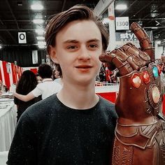 a young man standing next to a statue of a hand that is wearing a glove