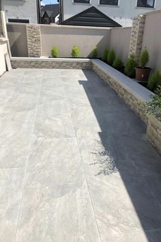 an outdoor patio with stone walls and planters on either side, next to a house