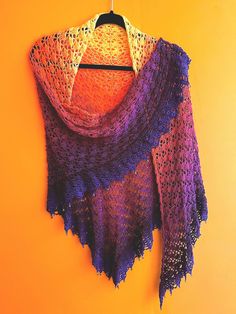 a crocheted shawl hanging on a yellow wall