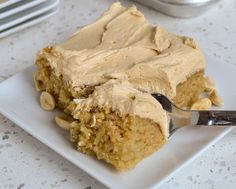 a piece of cake with peanut butter frosting on a white plate next to some plates