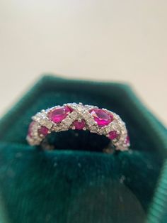 This beautiful ruby and Diamond ring is perfect for a stand alone band or stackable charm!  She is platinum.  4 oval rubies 4.5mm x 3.5mm approximately.  6 round rubies 2mm  53 brilliant cut natural diamonds 0.65 tcw. I color, VS1 clarity.  US size 5, sizable within reason. Luxury Modern Ruby Ring As Gift, Luxury Ruby Stackable Rings With Round Cut, Ruby Ring With Diamond Cut, Ruby Ring With Diamond Cut Round Band, Diamond Cut Ruby Ring, Oval Diamond Cut Ruby Ring, Red Ruby Ring With Marquise Cut Diamond, Luxury Heirloom Gia Certified Ruby Ring, Dazzling Ruby Ring With Vvs Clarity