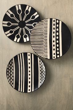 three black and white plates sitting on top of a wooden table