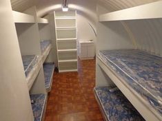 there are many bunk beds in the room with blue sheets on them and white shelves