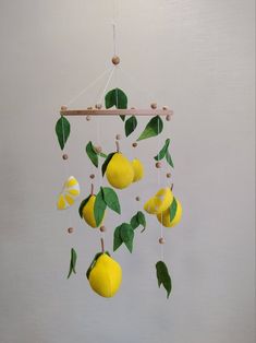 a mobile made to look like lemons hanging from a tree branch with green leaves