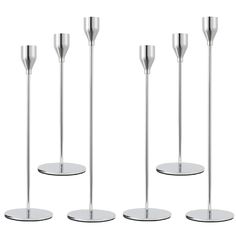 four metal candlesticks are lined up in a row on a white background,