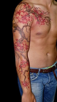 a man with tattoos on his arm and chest is standing in front of a black background