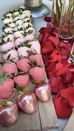 there are many different types of strawberries on the wooden table with flowers in vases