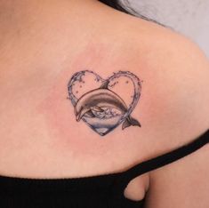 a woman's shoulder with a dolphin and heart tattoo on her left side ribcage