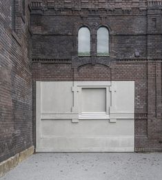 a white bench sitting in front of a brick building next to a wall with two windows