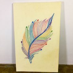 a piece of art with a colorful feather on it