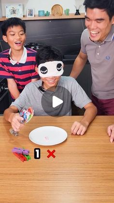 two boys and an adult are playing with toys on the table in front of them